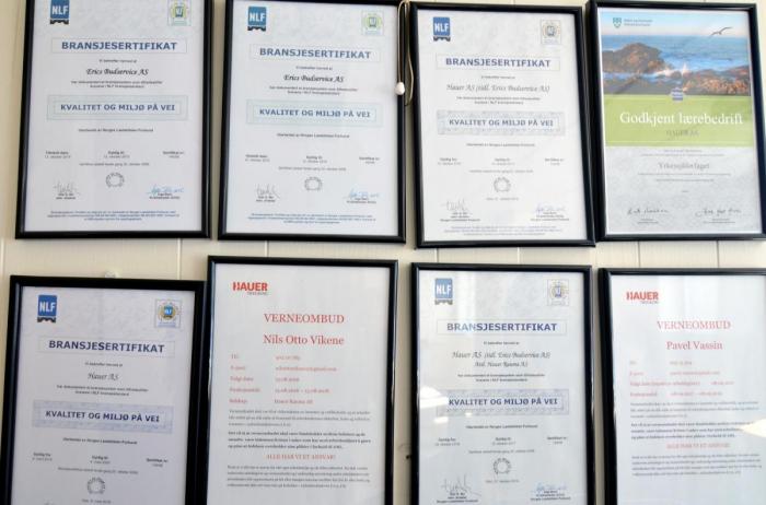 På kontorveggen henger bransjesertifikat og kursbevis, mange tilknyttet NLFs egne kvalitetssystemer. Foto: Heidi Rudaa
